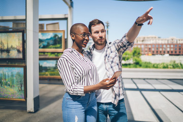 Cheerful young diverse couple checking location in street