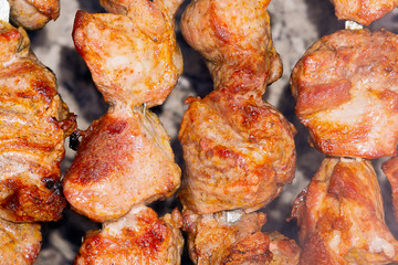 grilled pieces of meat on the coals close up