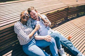 Multiracial couple enjoying sunlight lying on wooden platform
