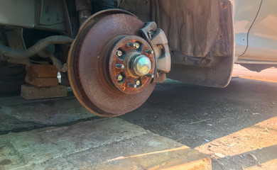 close up of rusty broken car with missing wheel