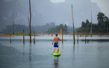 Young sports man is kayaking in lake.