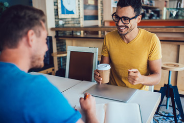 Cheerful caucasian brunette businessman having meeting interview with journalist talking to each...