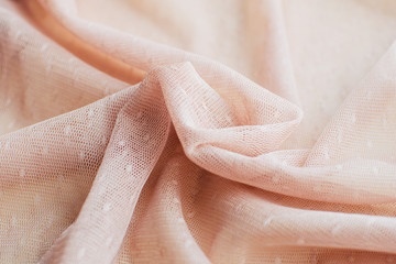 Feminine beige mesh fabric lay at the table.