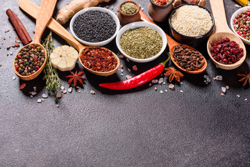 Spices and herbs over black stone background. Top view with free space for menu or recipes