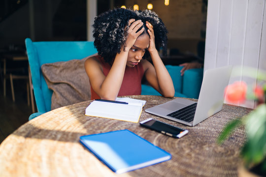 African American Worried Female Watching Laptop In Cafeteria