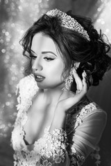 Black and white photo. Beautiful happy bride in white silk robe in her bedroom in a morning. Beauty woman with wedding hairstyle and makeup. Bride fashion. Jewelry and Beauty. 