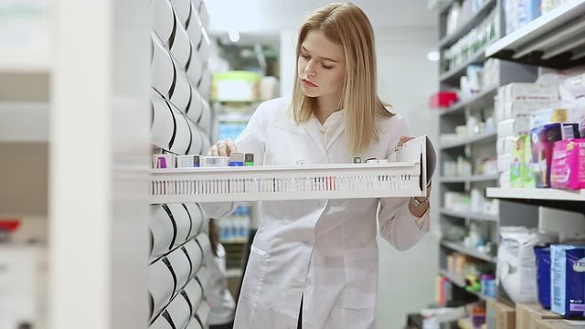 Young pharmacist is browsing rows of body care products in pharmacy