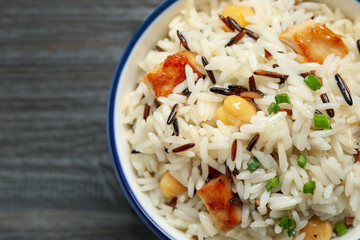 Delicious rice pilaf with chicken on black wooden table, closeup