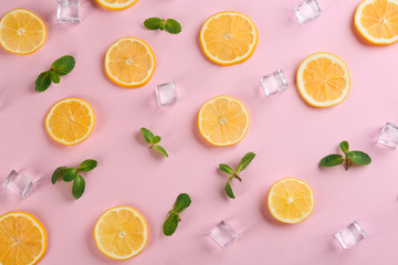 Lemonade layout with juicy lemon slices, mint and ice cubes on pink background, top view