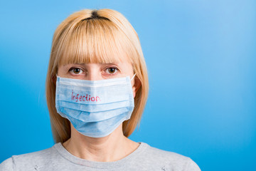 Portrait of woman wearing medical mask with infection text at blue background. Coronavirus concept. Respiratory protection