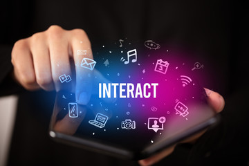 Businessman holding a foldable smartphone with INTERACT inscription, social media concept