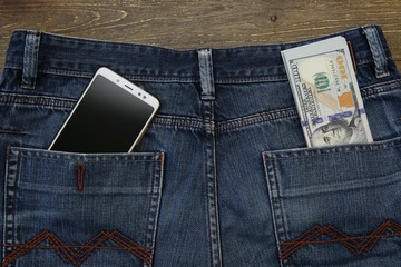 money dollars and mobile phone in jeans pocket on wooden rustic background. Business and finance tax payment concept. Background, pattern, banner, texture. Copy space.