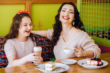 Beautiful mother with daughter. Family in a cafe. Girl with a dessert