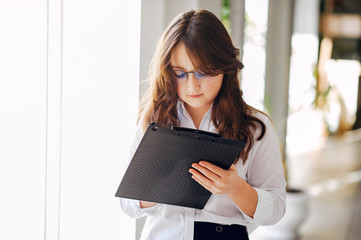 Girl in a office. Child in a white shirt. Lady with a notebook