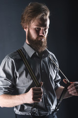 Young, handsome man with a beard posing on a black background in the studio.