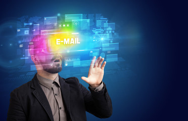 Businessman looking through Virtual Reality glasses with E-MAIL inscription, innovative security concept