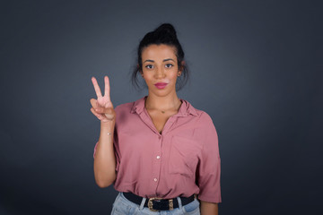 Young middle aged caucasian woman standing against gray wall showing and pointing up with fingers number two while smiling confident and happy.