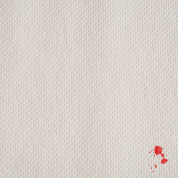 white paper towel with little red splatters in a corner