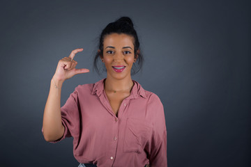 Blonde European woman over isolated background gesturing with hand showing small size, measure...