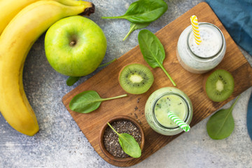 Healthy dieting and nutrition. Vegetarian concept. Blended Green detox vegetable smoothies with organic ingredients on a stone concrete tabletop. Top view flat lay background.