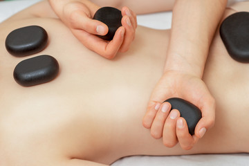 Young woman receiving a back massage with hot stones, close up.