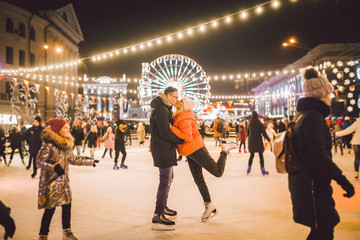 Beautiful Couple Ice Skating In City Centre. Young couple skating at a public ice skating rink outdoors. Theme ice skating rink and loving couple. Amazing winter holiday. Saint Valentine's Day