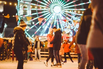 Foto op Plexiglas Couple in Love. Romantic Characters for Feast of Saint Valentine. True love. Happy Couple Having Fun at city ice rink in the evening. Happy romantic young couple enjoying together in skating-rink © Elizaveta