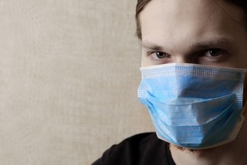 Man with a medical mask on his face, looking directly into the camera. 