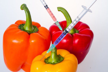 Genetically modified vegetables. GMO food concept. Syringes are stuck in vegetables with chemical additives. Injections into fruits and vegetables. Isolated on white background.