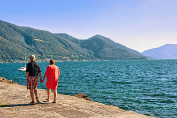 Couple passing by at the promenade at the luxurious resort in Ascona on Lake Maggiore in Ticino canton in Switzerland.