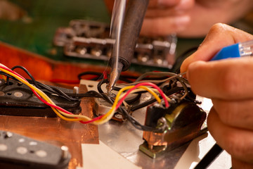 luthier soldering a guitar wire in his workshop