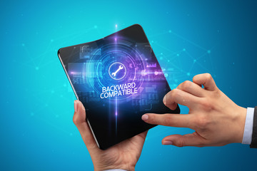 Businessman holding a foldable smartphone with COMPUTING inscription, new technology concept BACKWARD COMPATIBLE