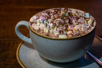 Cacao mug with marshmallows and cinnamon on a brown wooden table.