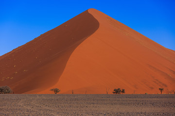 Fototapeta na wymiar Beautiful landscape with red huge sand dunes at sunset in desert. Sossusvlei, Namib Naukluft National Park, Namibia. Stunning natural geometry without people