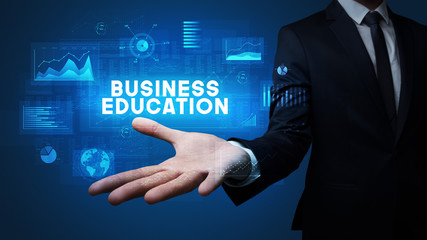 Hand of Businessman holding BUSINESS EDUCATION inscription, business success concept