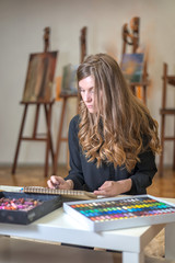 Portrait of a woman artist crayon painting in the art studio.