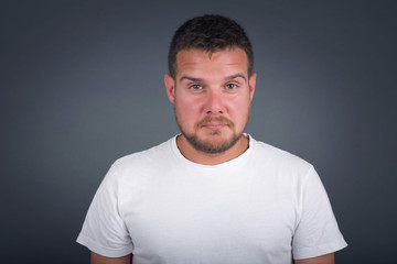 Fototapeta premium Beautiful face of sad man crying desperate and depressed with tears on his eyes suffering pain and depression isolated on grey background in sadness facial expression and emotion concept.