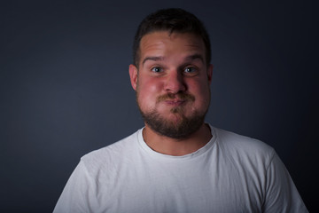 Fototapeta premium Handsome young man puffing cheeks with funny face. Mouth inflated with air, crazy expression.