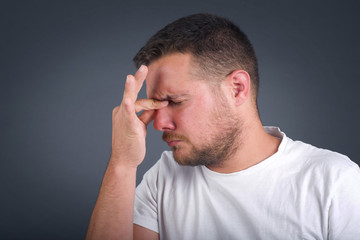 Obraz premium Very upset, charming, nice man touching nose between closed eyes standing outdoors, want to cry, having stressful relationship, worry about conflict with his lover or having troubles with work