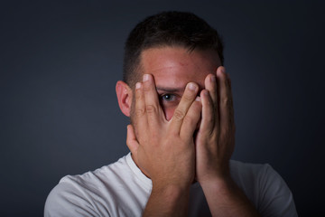 Anxiety - a conceptual image of a beautiful young caucasian man covering his face with his hands...