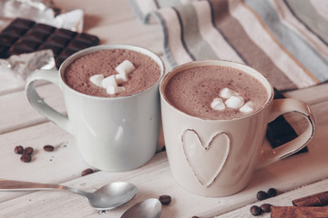 Two cups of hot cocoa with marshmallows and cinnamon sticks on wooden background. Love. Cocoa drink. Valentines day treat ideas.