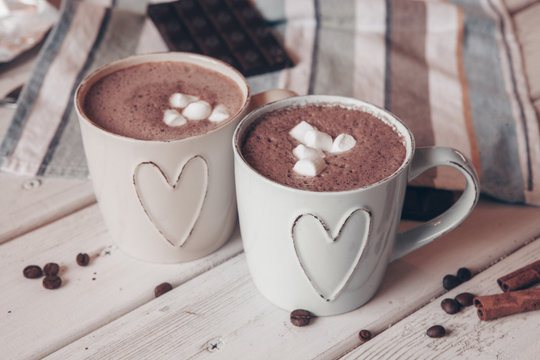 Two cups of hot cocoa with marshmallows and cinnamon sticks on wooden background. Love. Cocoa drink. Valentines day treat ideas.