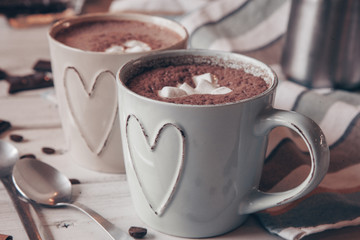 Two cups of hot cocoa with marshmallows and cinnamon sticks on wooden background. Love. Cocoa drink. Valentines day treat ideas.
