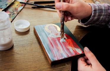Fototapeta na wymiar For protection wooden picture is process of applying сraquelure varnish on the product. Reproduction of the icon of St. Nicholas. Workflow of the artist in the studio. Brushes and paints. 
