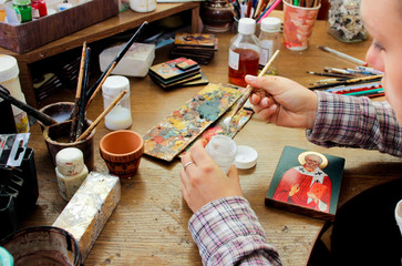 For protection wooden picture is process of applying сraquelure varnish on the product. Reproduction of the icon of St. Nicholas. Workflow of the artist in the studio. Brushes and paints.