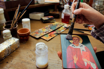 For protection wooden picture is process of applying сraquelure varnish on the product. Reproduction of the icon of St. Nicholas. Workflow of the artist in the studio. Brushes and paints.