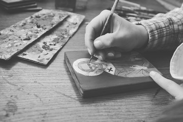 Artist paints eyes on picture. Close-up view. Black and white. Reproduction of the icon of St. Nicholas. Workflow of the artist in the studio.