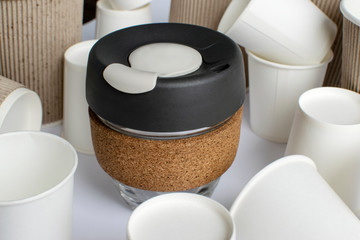 Reusable Coffee Eco Cup. Toughened Glass Cup & Natural Cork Band. Secure silicon lid. Reusable eco cup on the background of disposable cups. Eco-Friendly, Spill Proof Travel Mug with Lid | Black