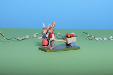 Fototapeta premium Two easterbunnies pull a cart with coloured eggs