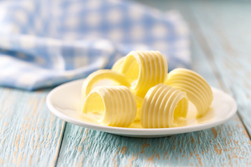 butter curls or rolls in ceramic bowl on a blue wooden table, selective focus.